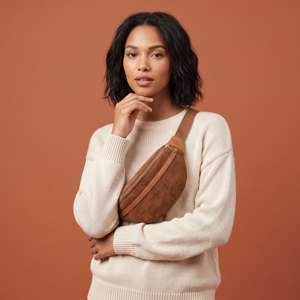 Femme portant le sac banane Capri Cinnamon en bandoulière sur un pull crème