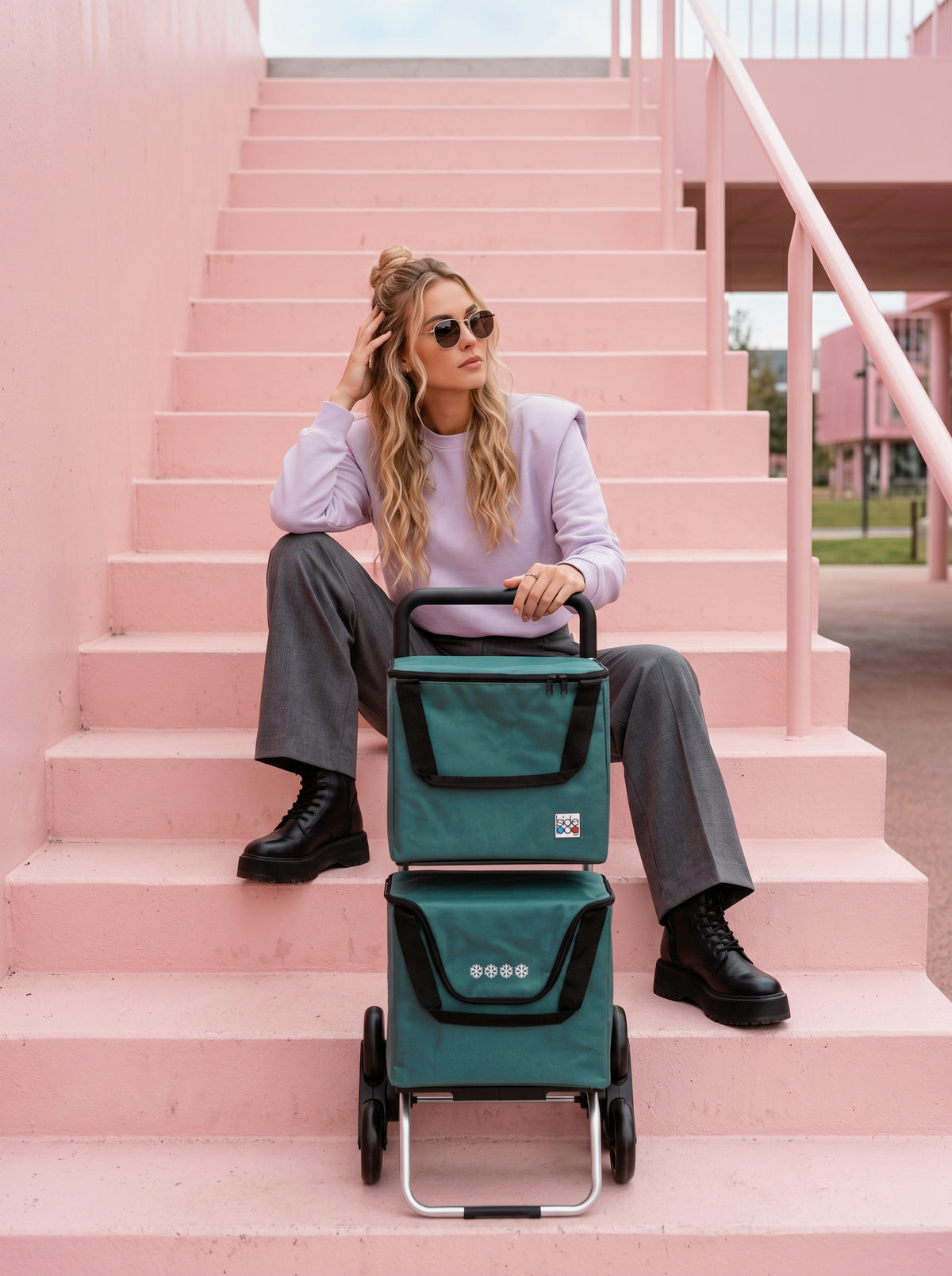Femme dans un escalier rose avec un SIDEBAG Modulo Bag vert, 6 roues