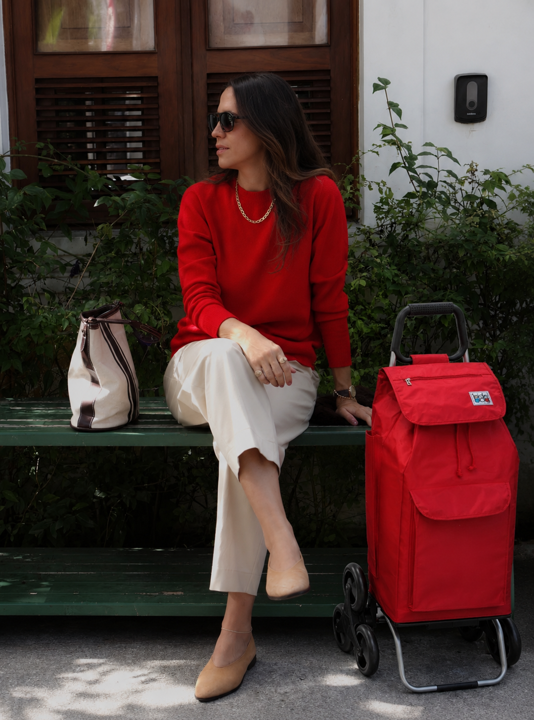 Femme assise sur un banc avec un chariot SIDEBAG rouge 6 roues
